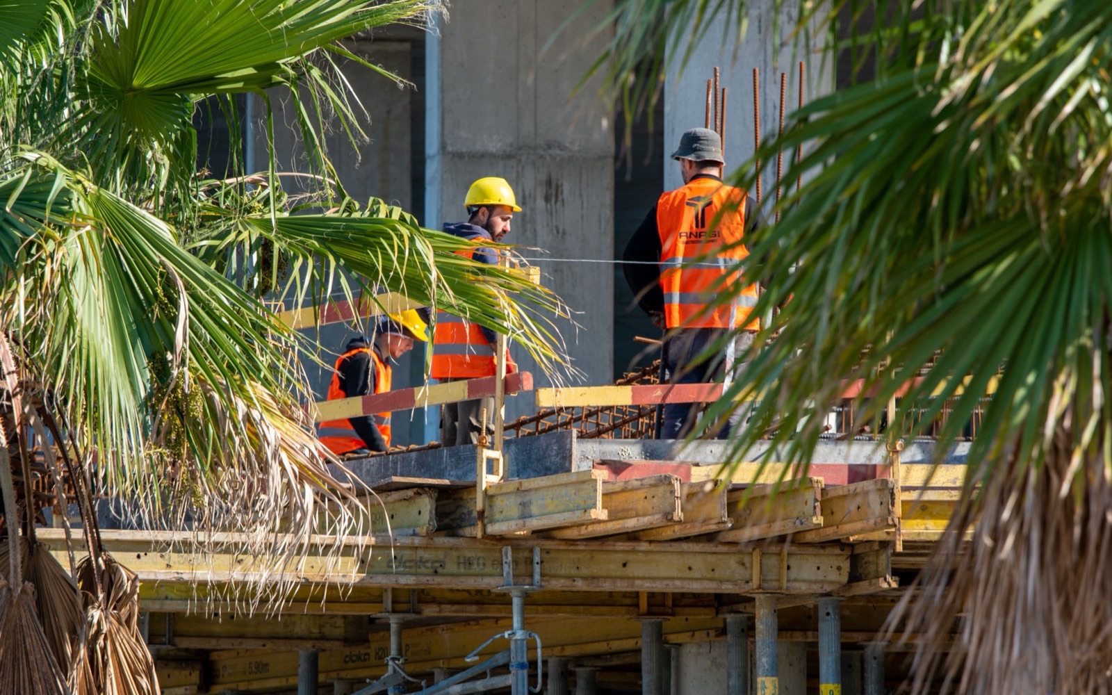 A construction crew in safety vests and hard hats working on formwork at an active job site