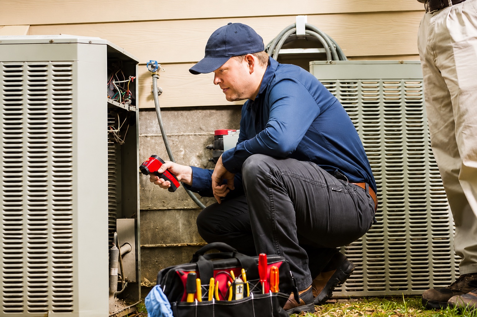 An HVAC technician testing an outdoor AC unit at a customer's home
